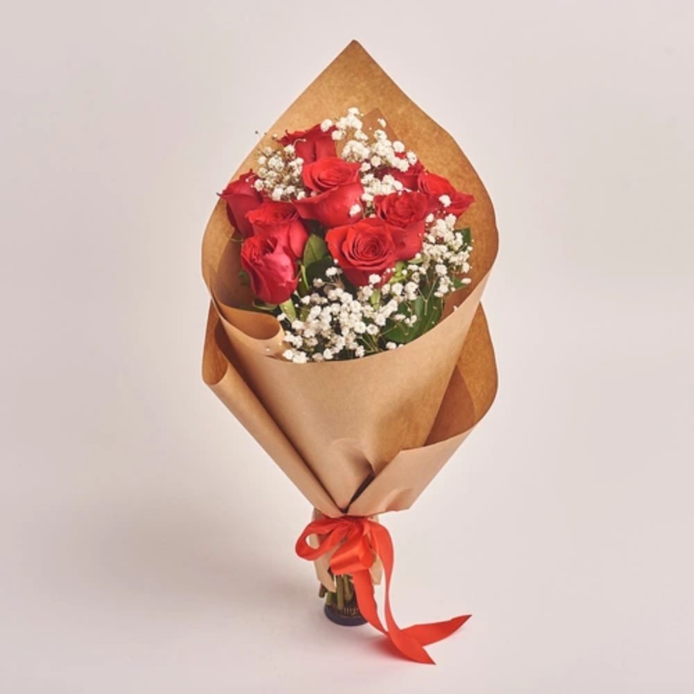 Handcrafted bouquet of fresh red roses with baby’s breath flowers wrapped in brown paper and tied with a red ribbon, elegant gift by Favish Blooms Dubai