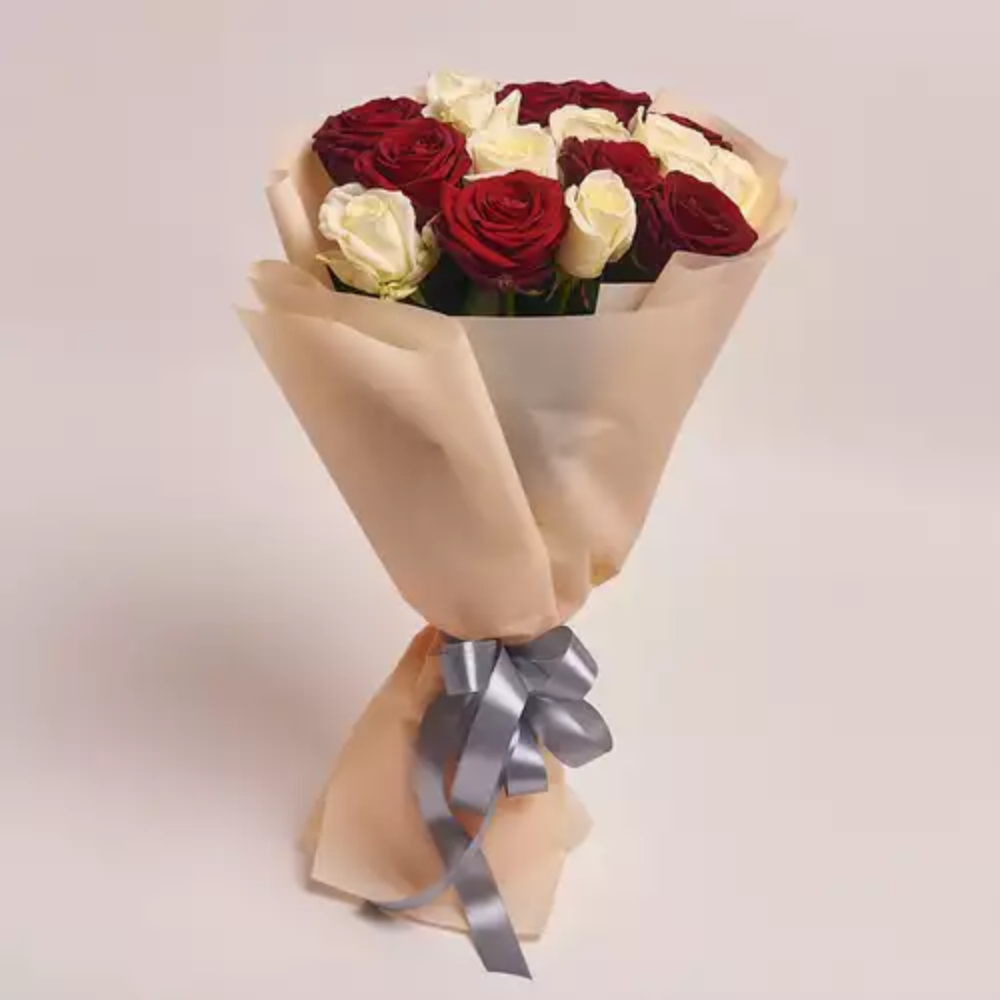Bouquet of red and white roses wrapped in beige paper with a silver ribbon.