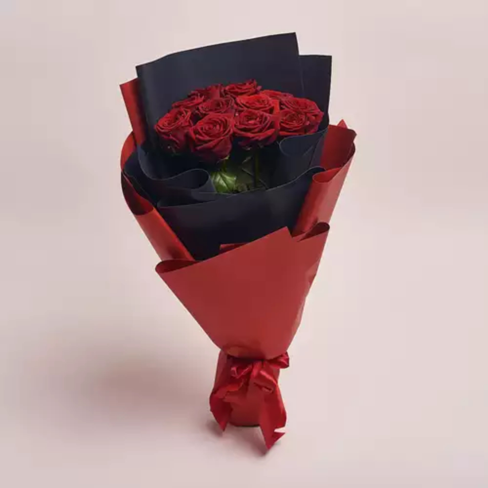 A bouquet of red roses wrapped in layered black and red paper, tied with a red ribbon