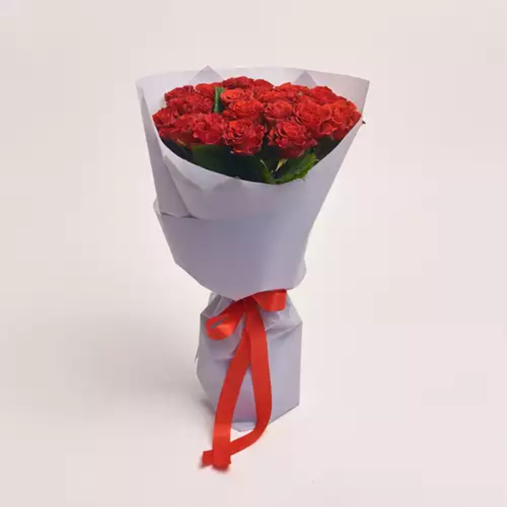 A bouquet of red roses wrapped in white paper and tied with a red satin ribbon