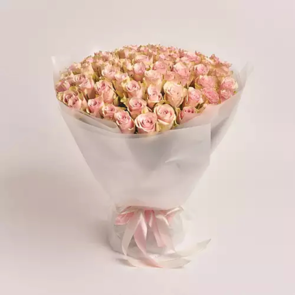A large bouquet of soft pink roses wrapped in white translucent paper and tied with a pink satin ribbon