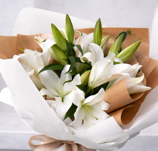 Fresh white lily bouquet in premium wrapping with a soft ribbon