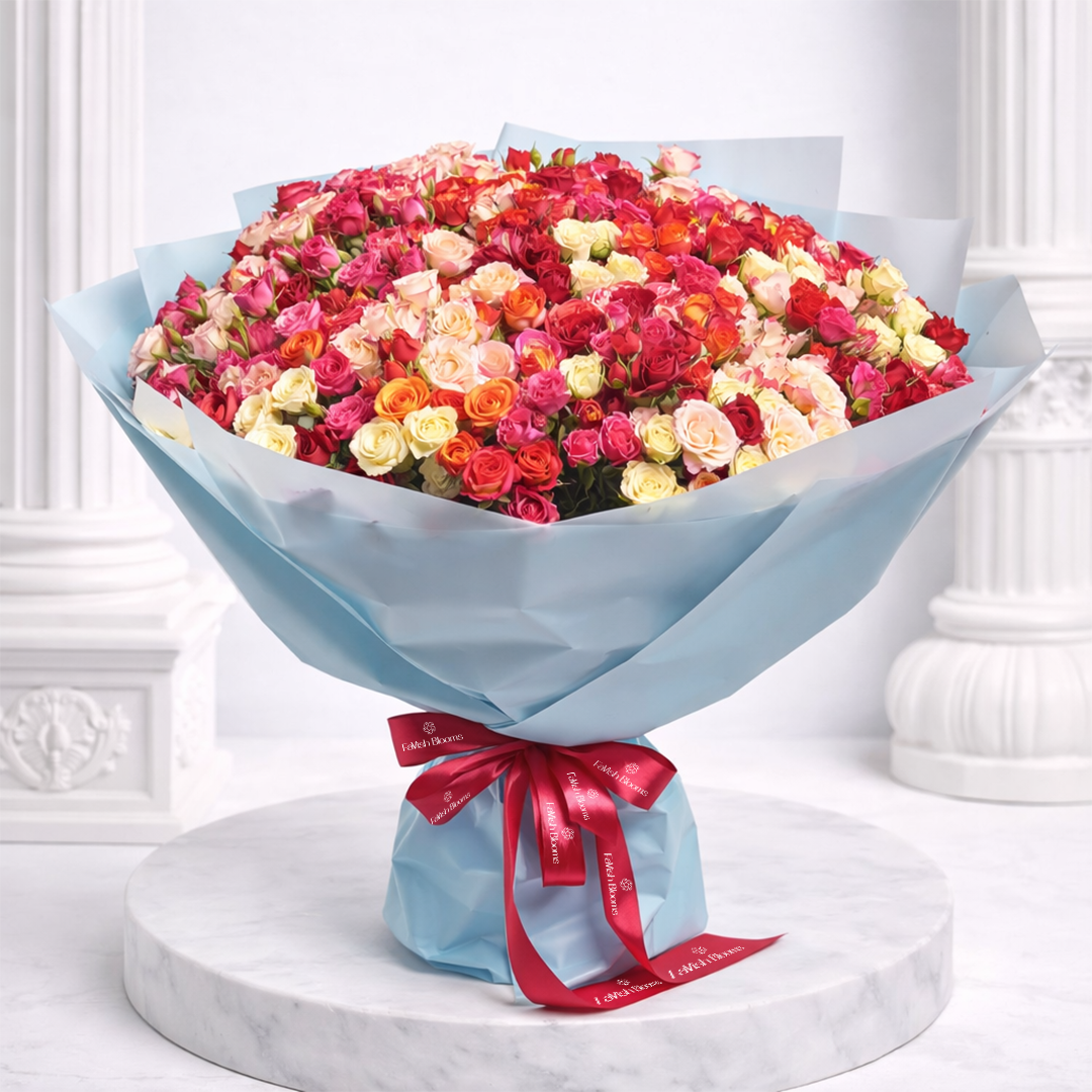 Luxury bouquet of multicolored roses in red, pink, orange, and cream, wrapped in light blue paper with a red ribbon