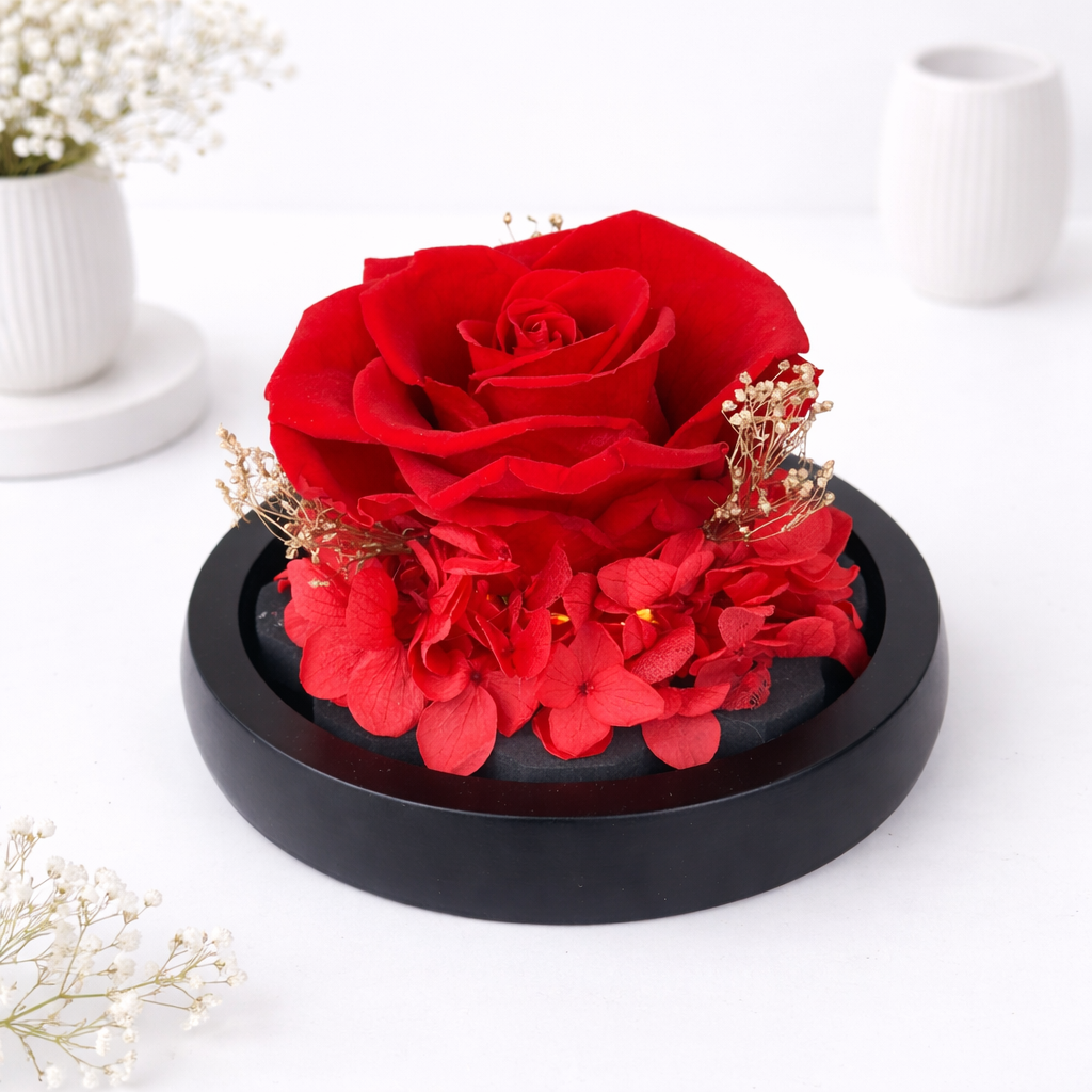 Close-up of a preserved red rose with hydrangeas and dried baby's breath on a black wooden base