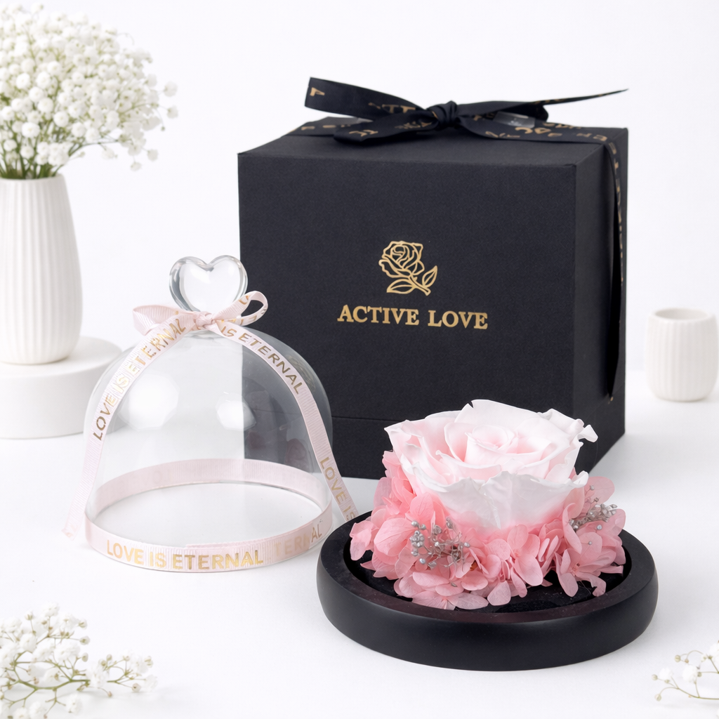 Pink preserved rose under a glass dome with a heart handle and "Love Is Eternal" ribbon, beside an Active Love black gift box.