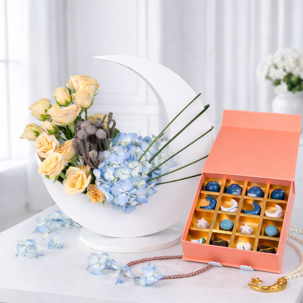Modern Thanksgiving floral display in a white crescent moon stand featuring peach roses, blue hydrangeas, and decorative greenery.