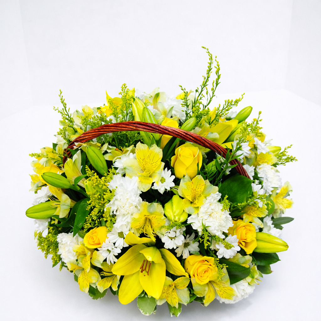 Abundant wicker basket arrangement of yellow lilies, roses, alstroemeria, white carnations, and daisies with green foliage on a white background.