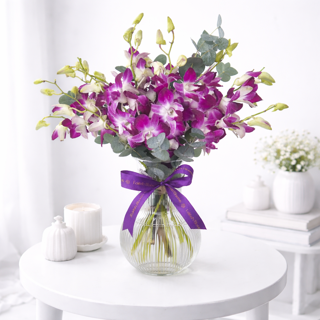Purple dendrobium orchids with eucalyptus in a glass vase tied with a FaVish Blooms purple ribbon