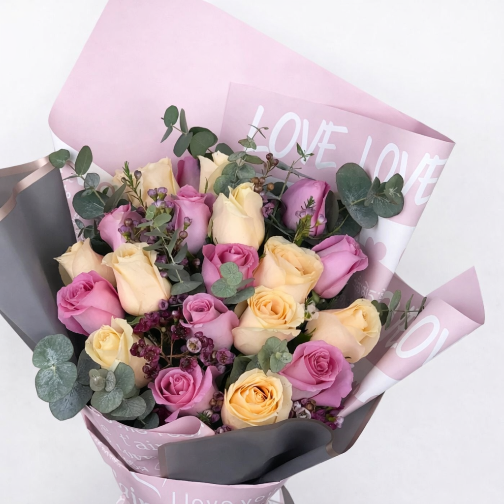 Close-up of mixed pink and cream roses with wax flowers and eucalyptus wrapped in pink "Love" printed paper