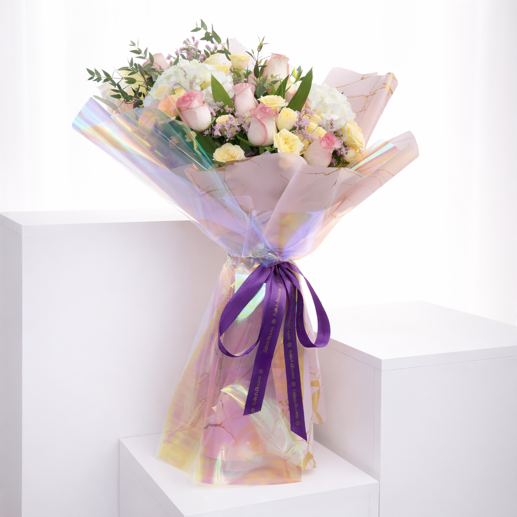 Luxury pink and cream rose bouquet in holographic iridescent wrapping on a white plinth.