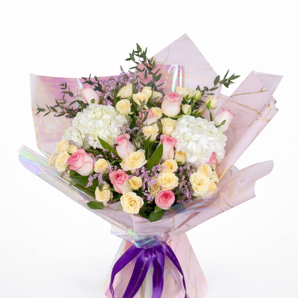 Close-up of pink roses, cream spray roses, and white hydrangea in luxury iridescent wrapping.