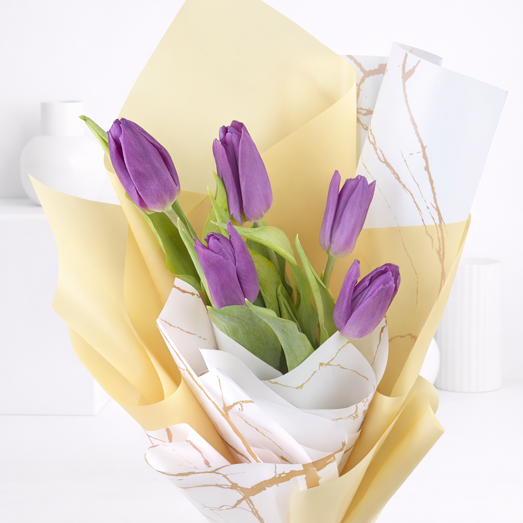 Close-up of purple tulips in gold and marble-print wrapping paper.