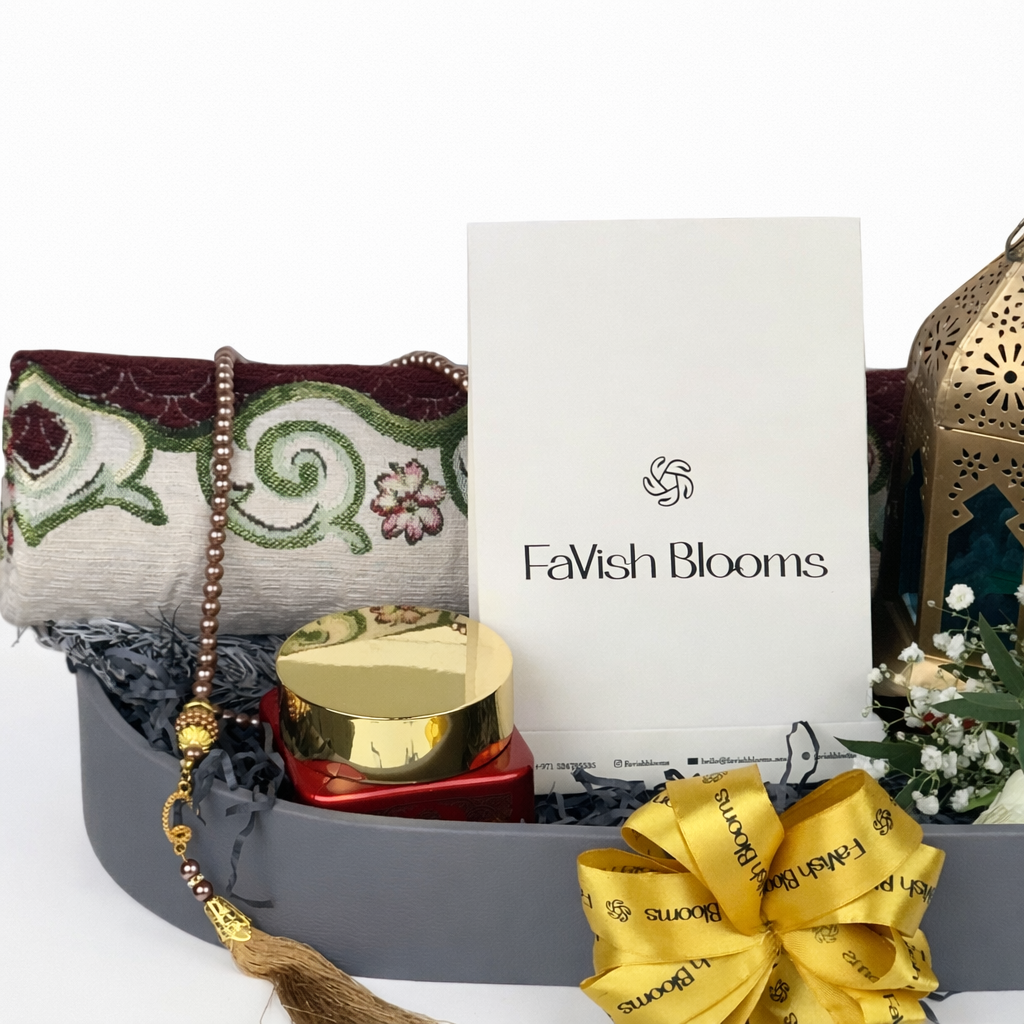 Close-up of FaVish Blooms Eid gift tray with branded card, prayer mat, tasbih, perfume, and gold ribbon.