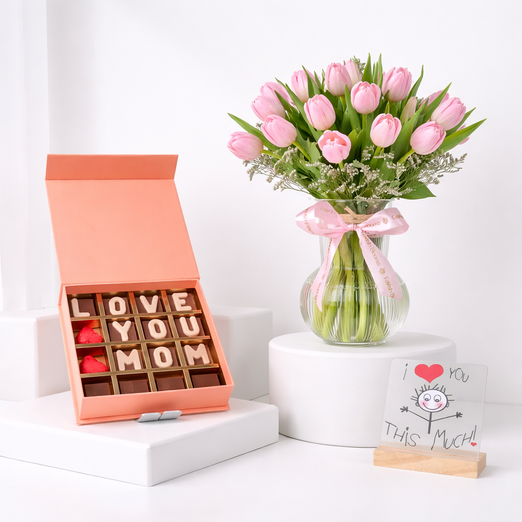 Pink tulips in a glass vase with "Love You Mom" chocolate letter box and "I Love You This Much" greeting card.