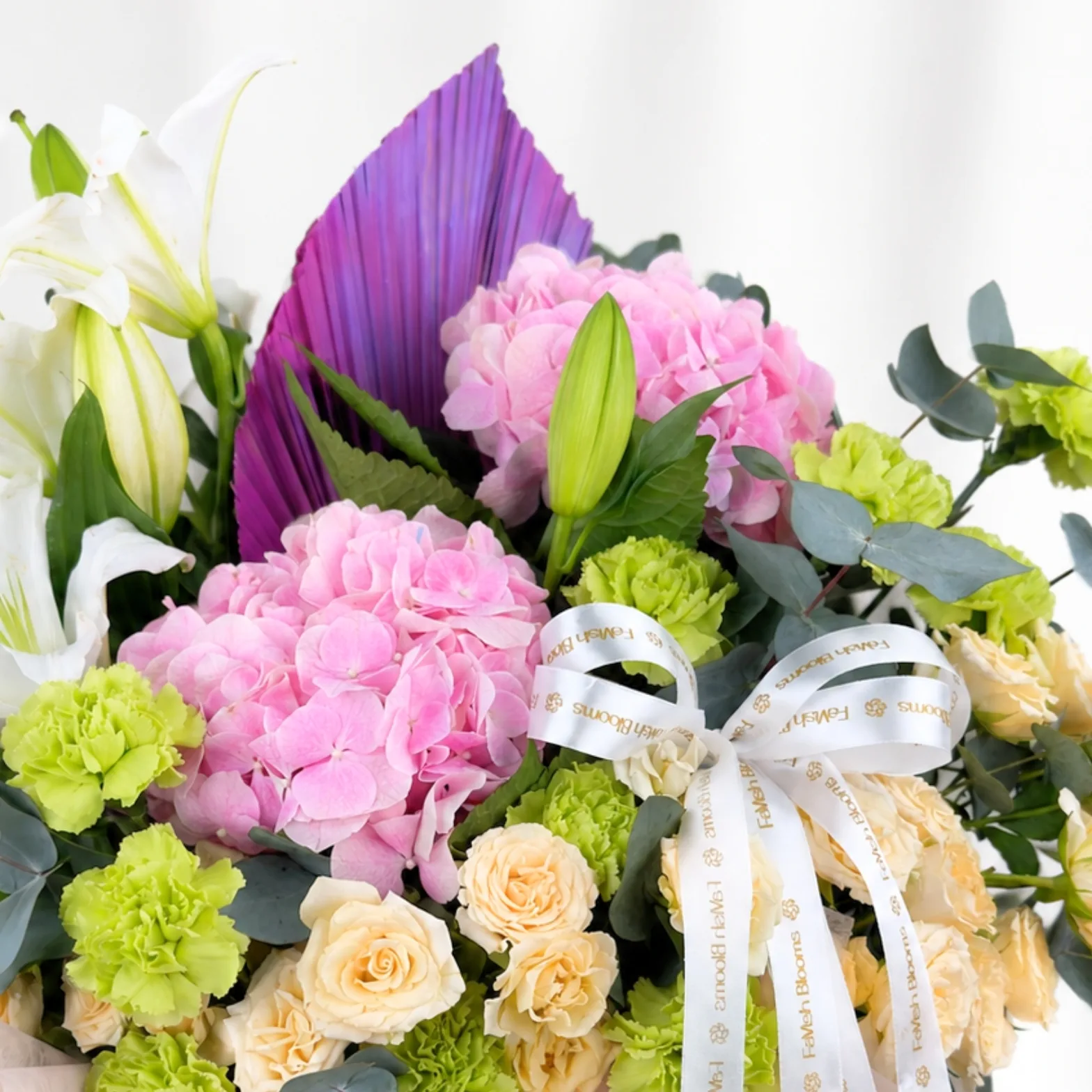 Close-up of pastel flowers with pink hydrangeas and purple dried palm leaf