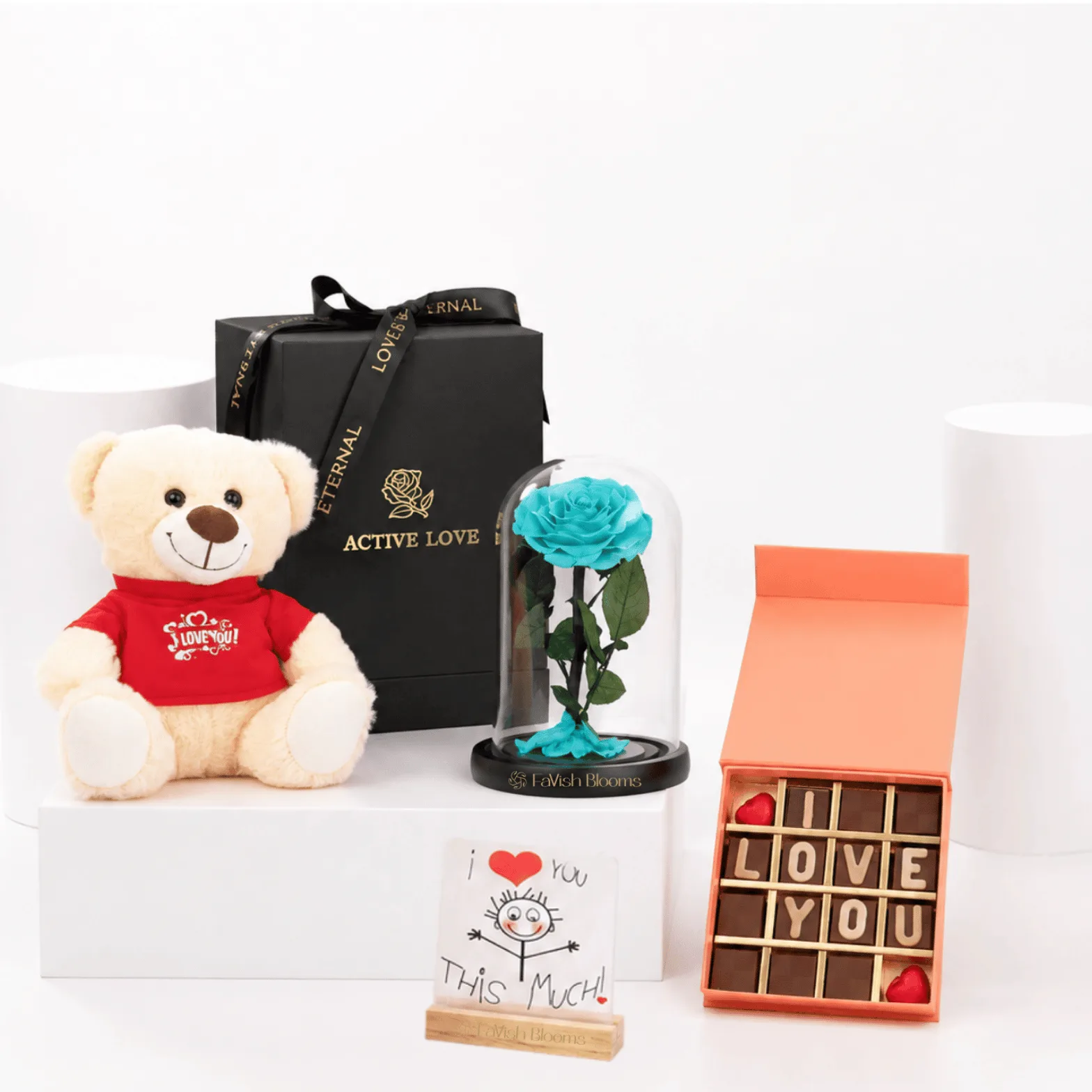 Luxury gift set with turquoise preserved rose, teddy bear, chocolate box, and romantic message card.