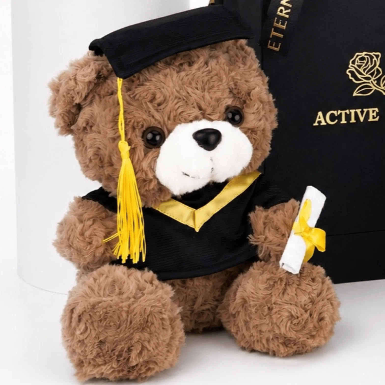 Graduation teddy bear wearing a black cap and gown, holding a diploma certificate.