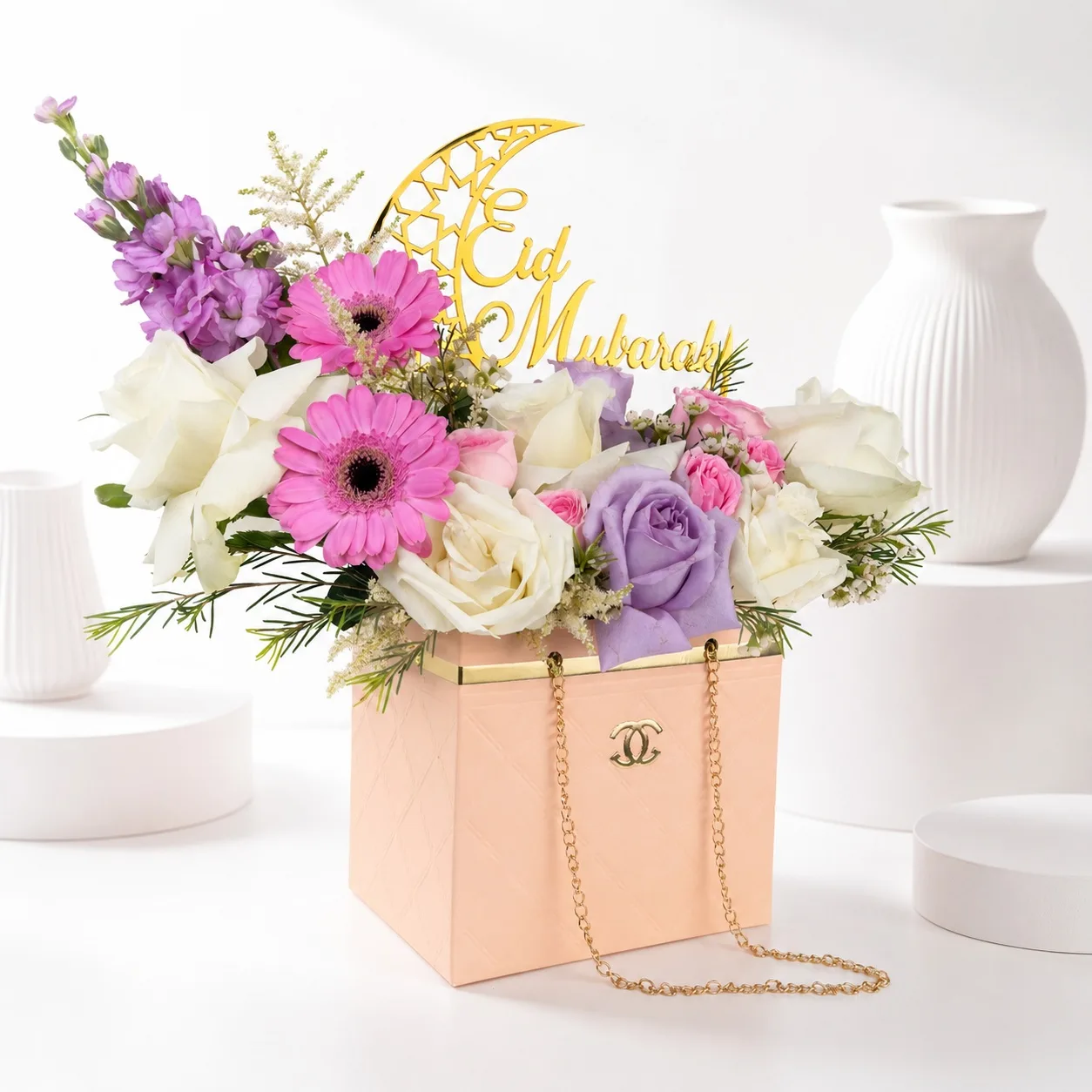 Elegant Eid Mubarak floral handbag arrangement with pastel roses, pink gerberas, and white blooms in a luxury peach gift bag.