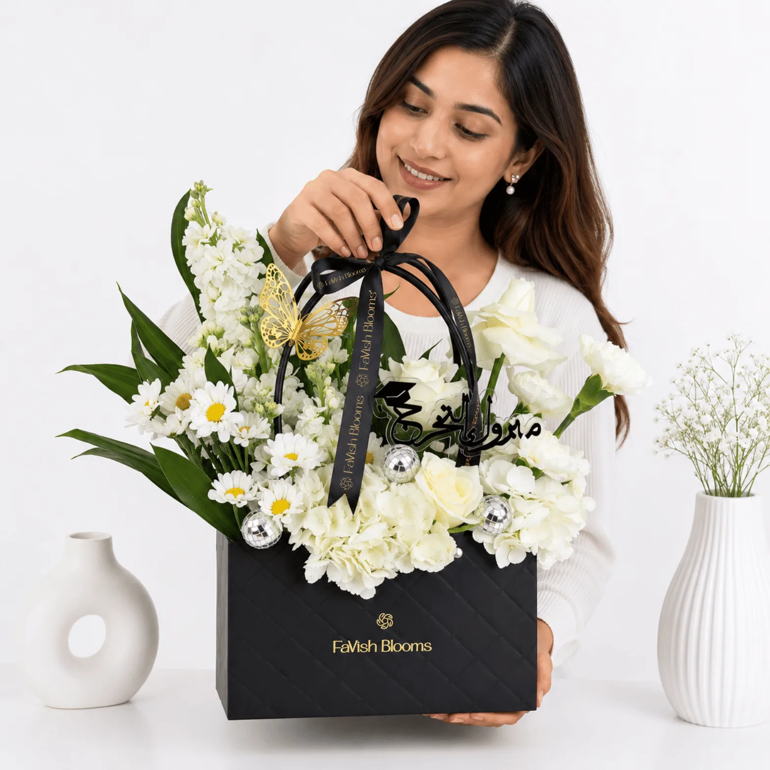 Woman holding an elegant Eid Mubarak flower arrangement featuring white roses, hydrangeas, daisies, and seasonal blooms in a luxury Favish Blooms gift bag.