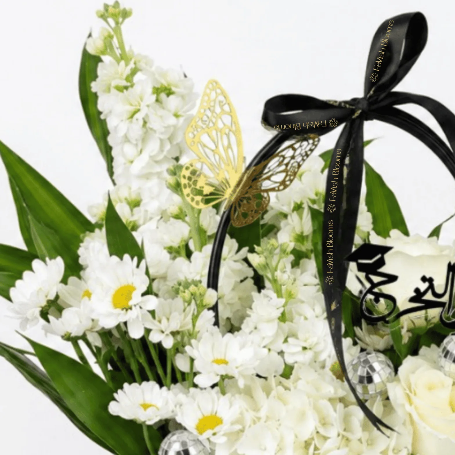 Close-up of a luxury Eid Mubarak floral arrangement featuring white daisies, hydrangeas, white roses, and a gold butterfly accent in a premium gift bag.